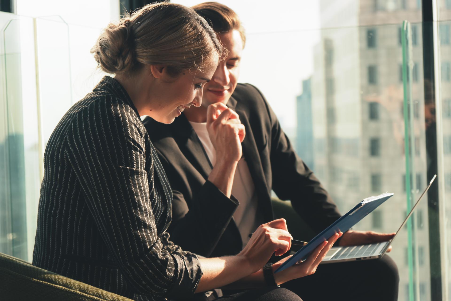 Kobieta i mężczyzna w biurze w trakcie rozmowy przy laptopach.