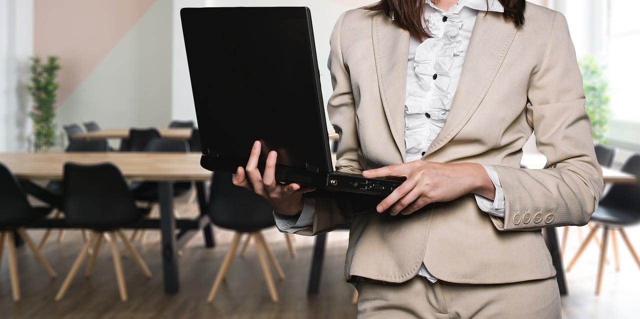 Kobieta trzymająca laptopa na spotkaniu biznesowym
