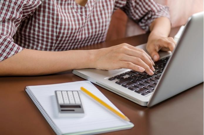 Osoba wpisuje treść na klawiaturze laptopa